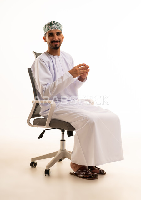 رجل أعمال عماني يجلس على كرسي مكتب بخلفية بيضاء
