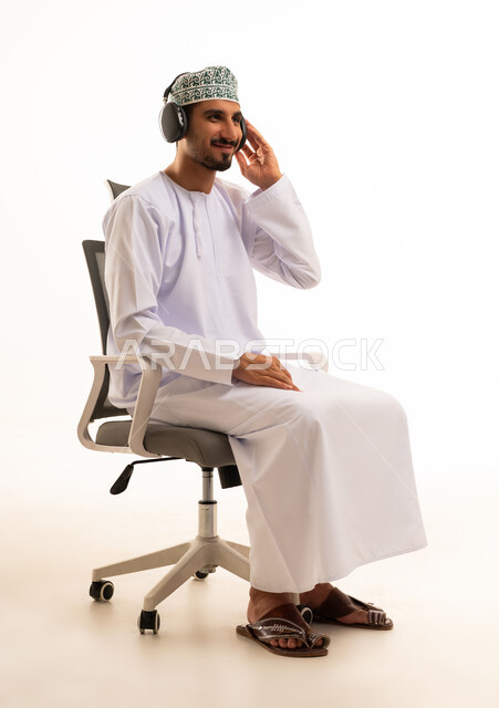 Omani Man in Traditional Dress Using Headphones