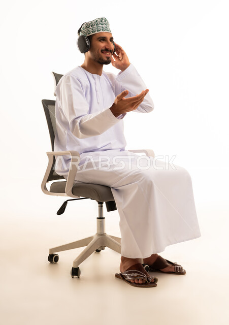 رجل عماني يرتدي سماعات على كرسي مكتب