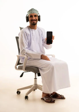 رجل عماني يرتدي سماعات ويحمل هاتفا ذكيا