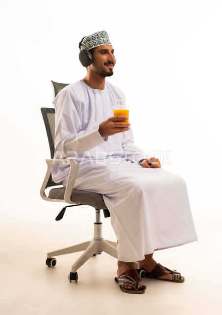 Omani Man with Headphones Holding Orange Juice in Studio