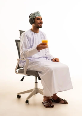 رجل عماني يرتدي سماعات ويحمل عصير برتقال في استوديو