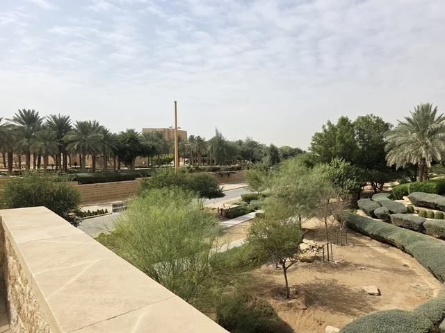 Heritage tourism areas in Saudi Arabia, the ancient architectural engineering art of the walls of Al-Salwah Palace in Al-Bujairi in Riyadh, an aerial image of the archaeological buildings and mud houses in Al-Turaif neighborhood in Diriyah, ancient historical archaeological landmarks, green palm trees.