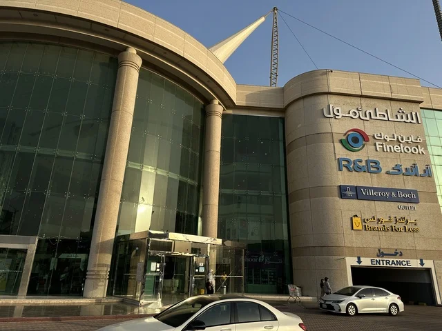 Traffic of cars in front of the entrance of the Beach Mall in Dammam, Eastern Province, Saudi Arabia, a comprehensive commercial and entertainment center, diverse restaurants and cafes, recreational areas for children and families, seasonal events and marketing activities, local and international stores and brands, a family-friendly atmosphere for all categories.