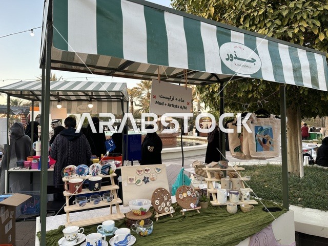 Outdoor shopping corners at the Jood Market in Prince Saud Park in Dhahran, Eastern Province, Saudi Arabia, an open community market that supports local projects, artisanal products, and homemade foods, family events and recreational activities, with a vibrant heritage and social atmosphere.