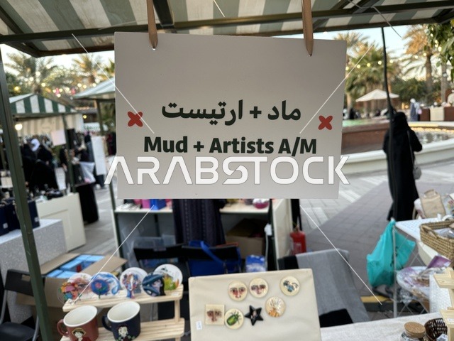 أركان تسوق خارجية في سوق جذور في حديقة الأمير سعود بمدينة الظهران، المنطقة الشرقية، المملكة العربية السعودية، سوق مجتمعي مفتوح يدعم المشاريع المحلية، منتجات حرفية وأطعمة منزلية، فعاليات عائلية وأنشطة ترفيهية، أجواء تراثية واجتماعية نابضة بالحياة