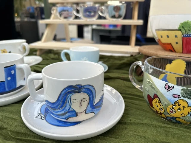 أركان تسوق خارجية في سوق جذور في حديقة الأمير سعود بمدينة الظهران، المنطقة الشرقية، المملكة العربية السعودية، سوق مجتمعي مفتوح يدعم المشاريع المحلية، منتجات حرفية وأطعمة منزلية، فعاليات عائلية وأنشطة ترفيهية، أجواء تراثية واجتماعية نابضة بالحياة