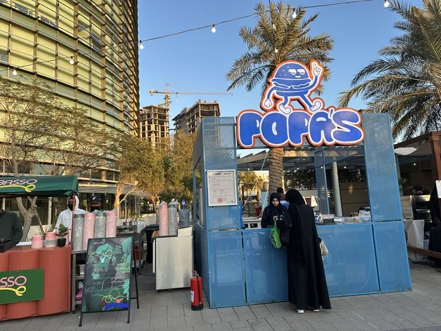 تجمع الزوار في سوق جذور في حديقة الأمير سعود بمدينة الظهران، المنطقة الشرقية، المملكة العربية السعودية، سوق مجتمعي مفتوح يدعم المشاريع المحلية، منتجات حرفية وأطعمة منزلية، أركان تسوق خارجية ، فعاليات عائلية وأنشطة ترفيهية، أجواء تراثية واجتماعية نابضة بالحياة