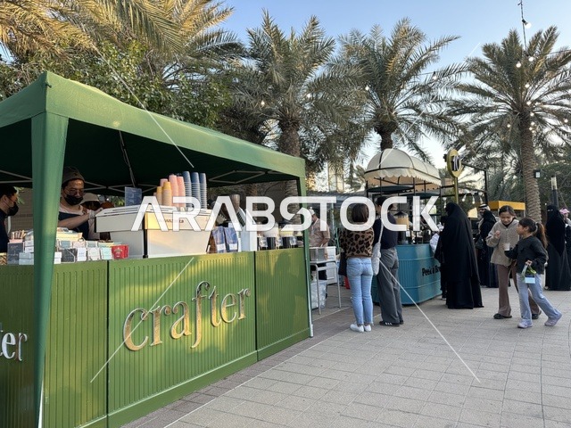 تجمع الزوار في سوق جذور في حديقة الأمير سعود بمدينة الظهران، المنطقة الشرقية، المملكة العربية السعودية، سوق مجتمعي مفتوح يدعم المشاريع المحلية، منتجات حرفية وأطعمة منزلية، أركان تسوق خارجية ، فعاليات عائلية وأنشطة ترفيهية، أجواء تراثية واجتماعية نابضة بالحياة