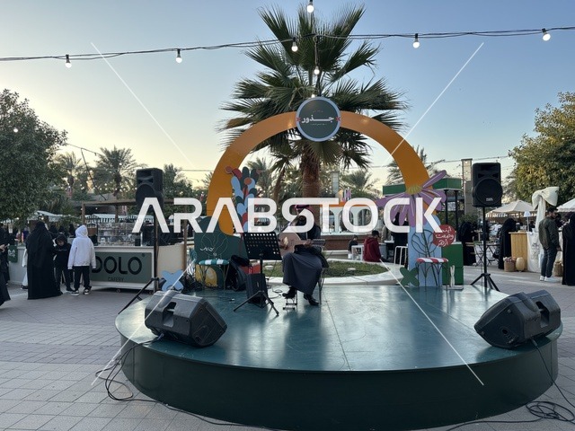 عرض موسيقي حي في سوق جذور في حديقة الأمير سعود بمدينة الظهران، المنطقة الشرقية، المملكة العربية السعودية، سوق مجتمعي مفتوح يدعم المشاريع المحلية، منتجات حرفية وأطعمة منزلية، أركان تسوق خارجية ، فعاليات عائلية وأنشطة ترفيهية، أجواء تراثية واجتماعية نابضة بالحياة