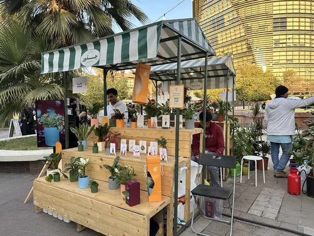 An open community market that supports local projects, Roots Market in Prince Saud Park in Dhahran, Eastern Province, Saudi Arabia, featuring artisanal products and homemade foods, outdoor shopping areas, family events, and recreational activities, with a vibrant heritage and social atmosphere.