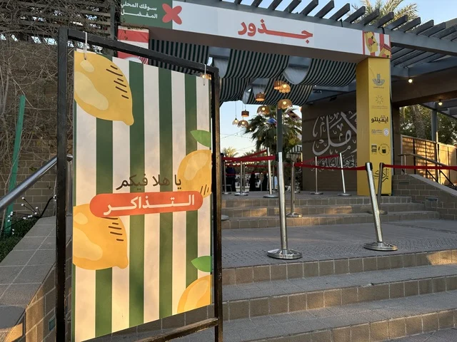 مدخل سوق جذور في حديقة الأمير سعود بمدينة الظهران، المنطقة الشرقية، المملكة العربية السعودية، منتجات حرفية وأطعمة منزلية، أركان تسوق خارجية ، فعاليات عائلية وأنشطة ترفيهية،  سوق مجتمعي مفتوح يدعم المشاريع المحلية، أجواء تراثية واجتماعية نابضة بالحياة