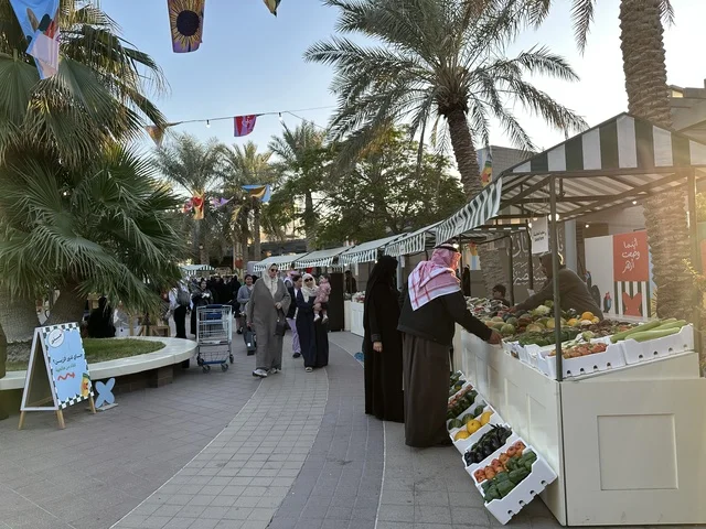 تجمع الزوار في سوق جذور في حديقة الأمير سعود بمدينة الظهران، المنطقة الشرقية، المملكة العربية السعودية، منتجات حرفية وأطعمة منزلية، أركان تسوق خارجية ، فعاليات عائلية وأنشطة ترفيهية،  سوق مجتمعي مفتوح يدعم المشاريع المحلية، أجواء تراثية واجتماعية نابضة بالحياة