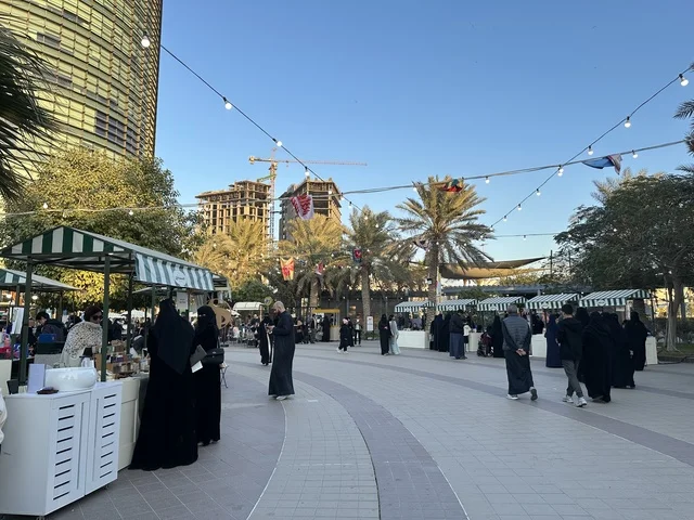 Visitors gathered at the Joudour Market in Prince Saud Park in Dhahran, Eastern Province, Saudi Arabia, featuring artisanal products and homemade foods, outdoor shopping areas, family events, and recreational activities. It is an open community market that supports local projects, with a vibrant heritage and social atmosphere.