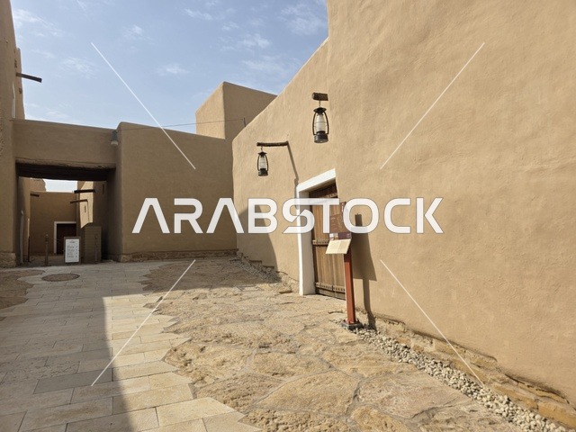 باب الخول لاحدى البيوت الطينية، أشجار النخيل الخضراء، أسوار الدرعية القديمة في مدينة الرياض في المملكة العربية السعودية، معالم أثرية تاريخية قديمة، الفن الهندسي المعماري القديم، صورة للمباني الأثرية والبيوت الطينية في حي الطريف في الدرعية