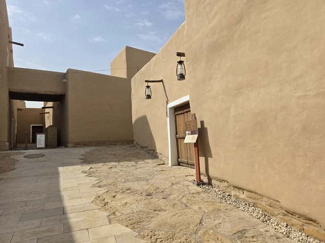 باب الخول لاحدى البيوت الطينية، أشجار النخيل الخضراء، أسوار الدرعية القديمة في مدينة الرياض في المملكة العربية السعودية، معالم أثرية تاريخية قديمة، الفن الهندسي المعماري القديم، صورة للمباني الأثرية والبيوت الطينية في حي الطريف في الدرعية