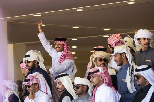 Expressions of enthusiasm and wide participation from camel owners, King Abdulaziz Camel Festival, Kingdom of Saudi Arabia, a major national heritage event, competitions and beauty of camels, shows and auctions, cultural and heritage activities, festive atmosphere reflecting the authenticity of the Saudi heritage.