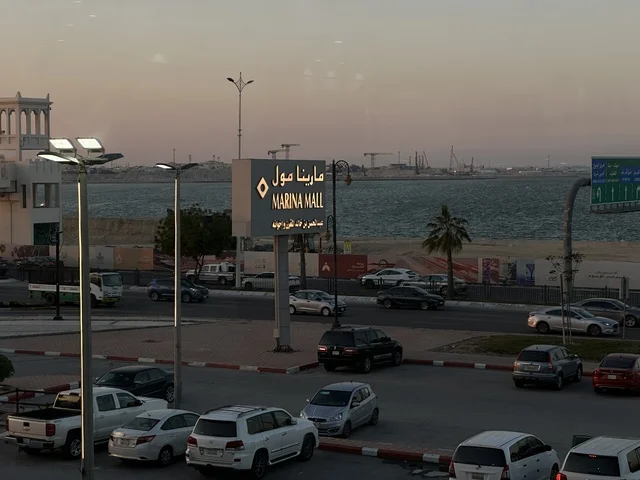 وقوف السيارات في الباركينج الخارجي لمارينا مول في مدينة الدمام، المنطقة الشرقية، المملكة العربية السعودية، مركز تسوق وترفيه مطل على الواجهة البحرية، متاجر وعلامات تجارية متنوعة، مطاعم ومقاهي بإطلالات بحرية، مرافق ترفيهية وخدمية، وجهة عائلية تجمع التسوق والترفيه