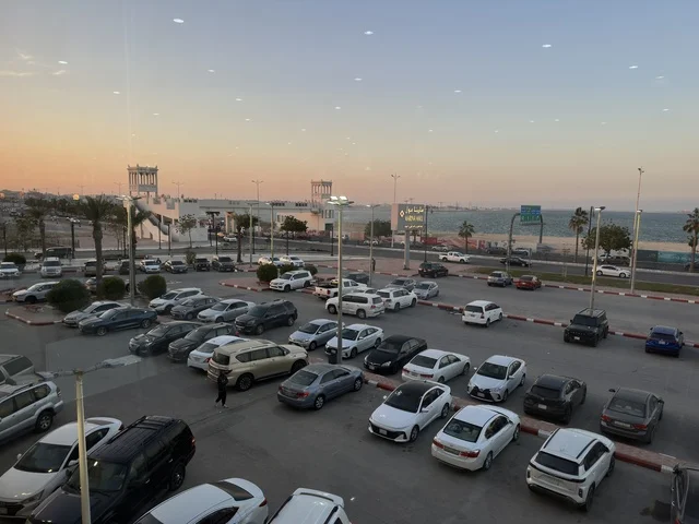 وقوف السيارات في الباركينج الخارجي لمارينا مول في مدينة الدمام، المنطقة الشرقية، المملكة العربية السعودية، مركز تسوق وترفيه مطل على الواجهة البحرية، متاجر وعلامات تجارية متنوعة، مطاعم ومقاهي بإطلالات بحرية، مرافق ترفيهية وخدمية، وجهة عائلية تجمع التسوق والترفيه