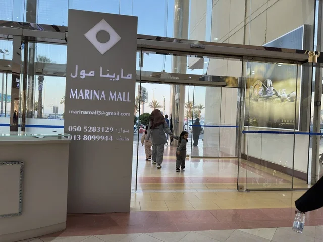 مدخل مارينا مول في مدينة الدمام، المنطقة الشرقية، المملكة العربية السعودية، مركز تسوق وترفيه مطل على الواجهة البحرية، متاجر وعلامات تجارية متنوعة، مطاعم ومقاهي بإطلالات بحرية، مرافق ترفيهية وخدمية، وجهة عائلية تجمع التسوق والترفيه