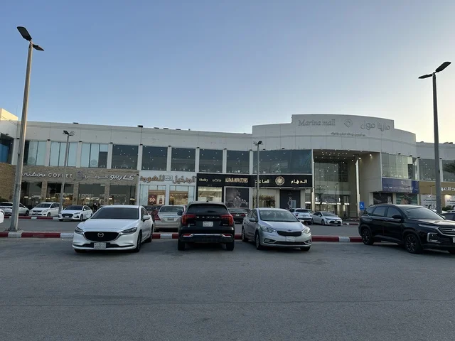 وقوف السيارات فى الباركينج الخارجي امام مارينا مول في مدينة الدمام، المنطقة الشرقية، المملكة العربية السعودية، مركز تسوق وترفيه مطل على الواجهة البحرية، متاجر وعلامات تجارية متنوعة، مطاعم ومقاهي بإطلالات بحرية، مرافق ترفيهية وخدمية، وجهة عائلية تجمع التسوق والترفيه
