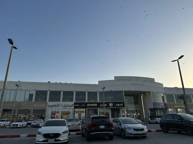 وقوف السيارات فى الباركينج الخارجي امام مارينا مول في مدينة الدمام، المنطقة الشرقية، المملكة العربية السعودية، مركز تسوق وترفيه مطل على الواجهة البحرية، متاجر وعلامات تجارية متنوعة، مطاعم ومقاهي بإطلالات بحرية، مرافق ترفيهية وخدمية، وجهة عائلية تجمع التسوق والترفيه