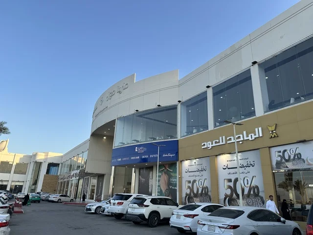 انتظار السيارات في المواقف الخارجية لمارينا مول في مدينة الدمام، المنطقة الشرقية، المملكة العربية السعودية، مركز تسوق وترفيه مطل على الواجهة البحرية، متاجر وعلامات تجارية متنوعة، مطاعم ومقاهي بإطلالات بحرية، مرافق ترفيهية وخدمية، وجهة عائلية تجمع التسوق والترفيه