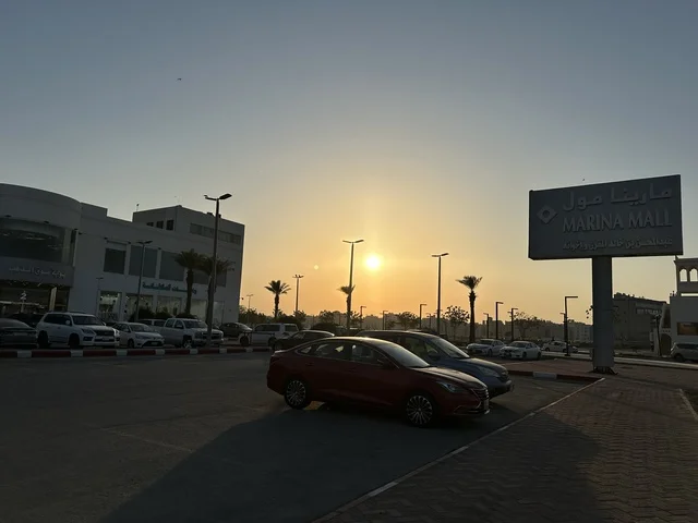 انتظار السيارات في المواقف الخارجية لمارينا مول في مدينة الدمام، المنطقة الشرقية، المملكة العربية السعودية، مركز تسوق وترفيه مطل على الواجهة البحرية، متاجر وعلامات تجارية متنوعة، مطاعم ومقاهي بإطلالات بحرية، مرافق ترفيهية وخدمية، وجهة عائلية تجمع التسوق والترفيه