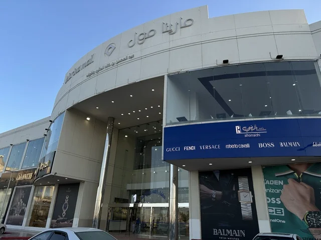 مدخل مارينا مول في مدينة الدمام، المنطقة الشرقية، المملكة العربية السعودية، مركز تسوق وترفيه مطل على الواجهة البحرية، متاجر وعلامات تجارية متنوعة، مطاعم ومقاهي بإطلالات بحرية، مرافق ترفيهية وخدمية، وجهة عائلية تجمع التسوق والترفيه