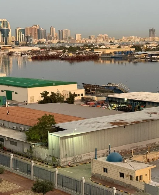 البواخر في ميناء عجمان صباحا، دولة الإمارات العربية المتحدة، مشهد بحري هادئ يعكس بداية يوم جديد، ألوان السماء الدافئة تنعكس على سطح البحر، حركة السفن في الميناء، أجواء صباحية ناعمة تجمع بين النشاط البحري والطبيعه