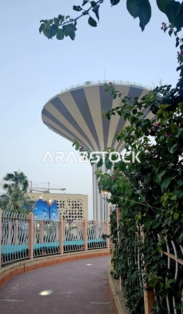 برج مياه يقع داخل حديقة حضرية بالمملكة العربية السعودية، معلم بنية تحتية بتصميم حديث، مساحات خضراء محيطة، اندماج المرافق الخدمية مع التخطيط العمراني.
