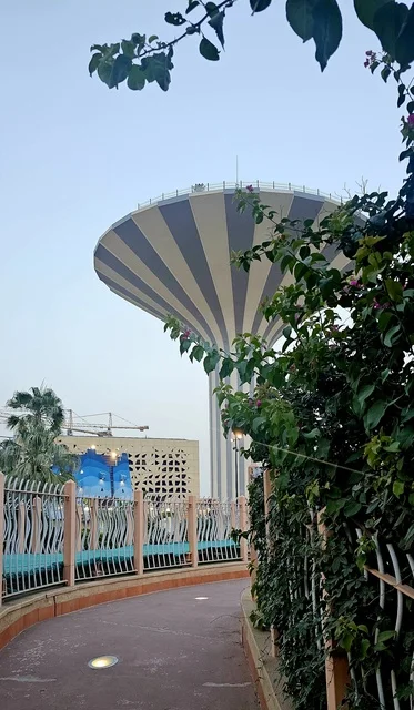 برج مياه يقع داخل حديقة حضرية بالمملكة العربية السعودية، معلم بنية تحتية بتصميم حديث، مساحات خضراء محيطة، اندماج المرافق الخدمية مع التخطيط العمراني.