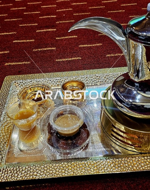 The Arabic coffee pot with cups on a tray in a traditional gathering is a symbol of authentic Arab hospitality, creating a heritage atmosphere that reflects generosity and social customs in the Kingdom of Saudi Arabia.