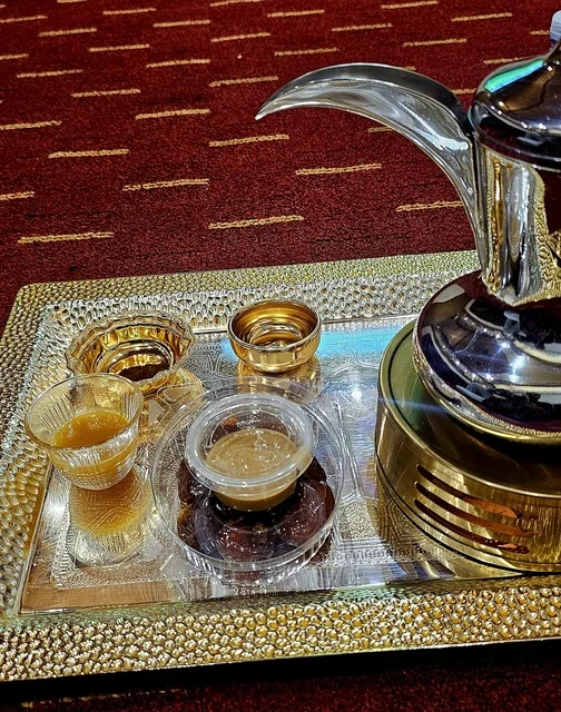The Arabic coffee pot with cups on a tray in a traditional gathering is a symbol of authentic Arab hospitality, creating a heritage atmosphere that reflects generosity and social customs in the Kingdom of Saudi Arabia.