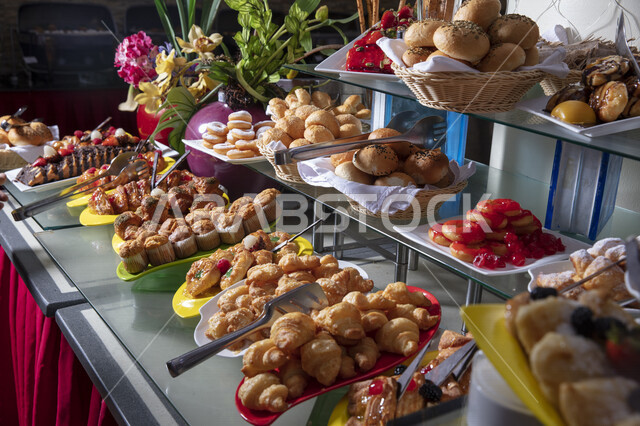 صورة لمائدة طعام مفتوحة في إحدى المطاعم بالمملكة العربية السعودية ، بوفيه طعام ، أطباق متنوعة من المخبوزات الساخنة اللذيذة ، حلويات شعبية طازجة ، مخبوزات ، أقراص الكعك المجوفة المحشوة ، السكريات والحلويات الشهية