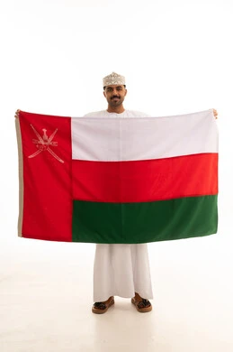 رجل عُماني يحمل علم السلطنة على خلفية بيضاء