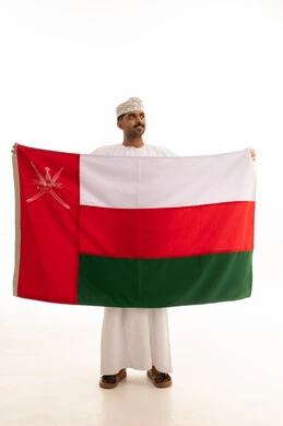 رجل عماني يحمل علم سلطنة عمان بخلفية بيضاء