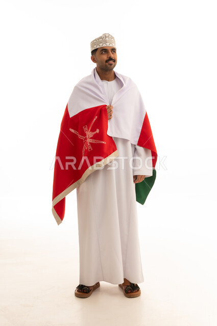 رجل عماني بالزي التقليدي يرتدي علم سلطنة عمان