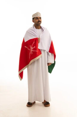 رجل عماني بالزي التقليدي يرتدي علم سلطنة عمان