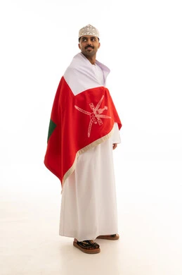 رجل عماني باللباس التقليدي مع علم سلطنة عمان