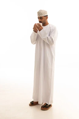 رجل عماني بالزي التقليدي يشرب من كوب أبيض