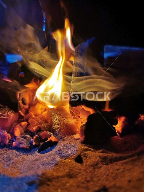 النيران المشتعلة  في الحطب ، اللهب الأحمر المشتعل في رحلة تخييم بالصحراء ، جمال الطبيعة في صحراء المملكة العربية السعودية ليلاً ، جلسة بر عربية شعبية في صحراء السعودية , مخيم شعبي في صحاري المملكة