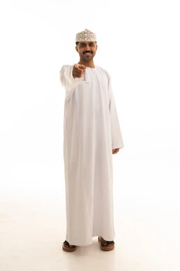 رجل عماني مبتسم يشير إلى الكاميرا بخلفية بيضاء