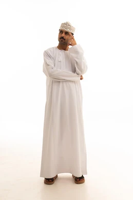 رجل عماني باللباس التقليدي يفكر أمام خلفية بيضاء