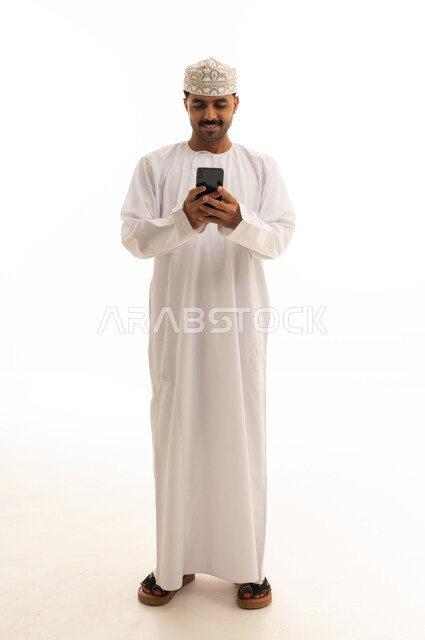 Omani Man in Traditional Dishdasha Using Smartphone