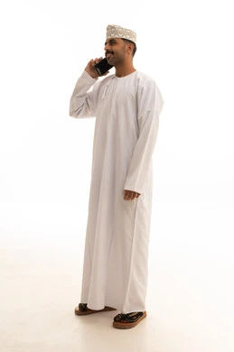 رجل عماني بالزي التقليدي يستخدم الهاتف الذكي