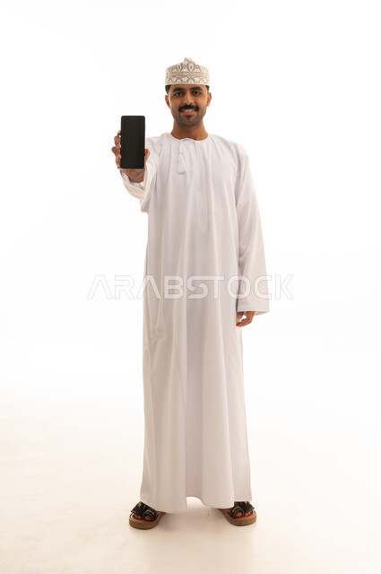 رجل عماني بالزي التقليدي يمسك هاتف ذكي