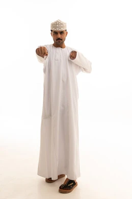 رجل عُماني بالدشداشة التقليدية يشير للأمام