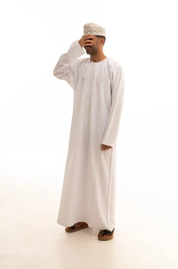 رجل عماني بالزي التقليدي يغطي وجهه بيده