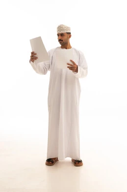 رجل عماني بالزي التقليدي يراجع أوراق رسمية